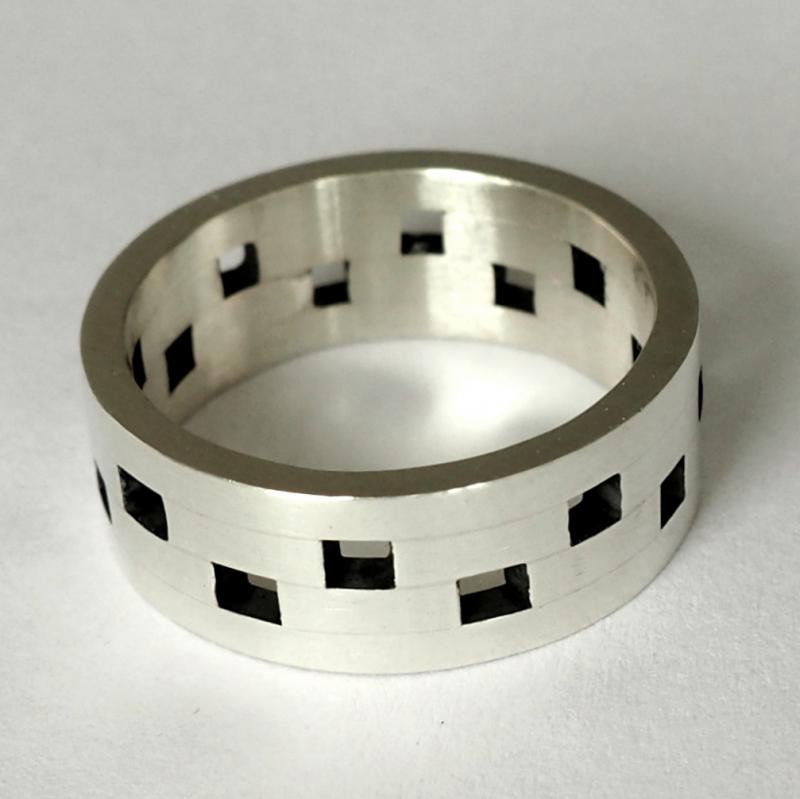 Zilveren ring met versprongen vierkantjes.